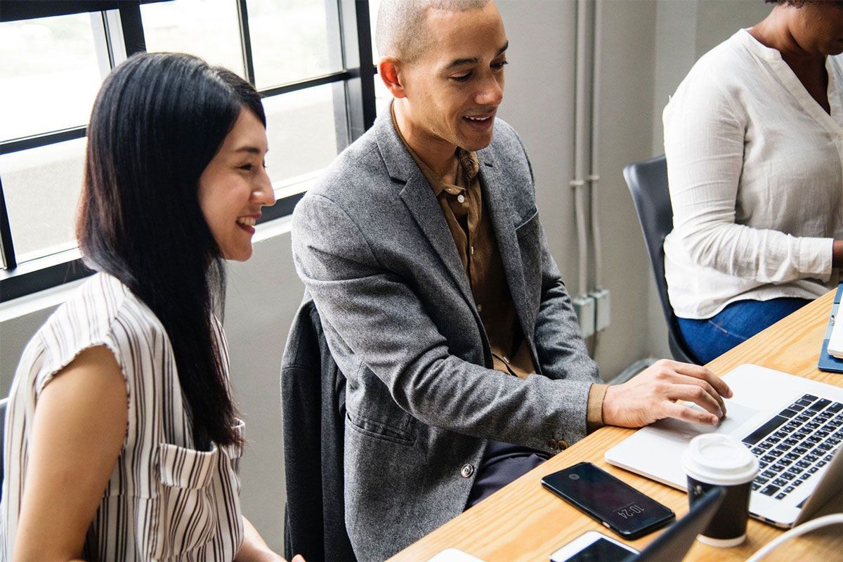Man showing something to a girl on a laptop
